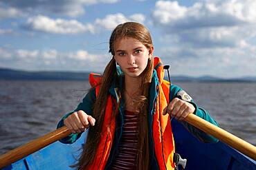 Caucasian girl rowing canoe in lake