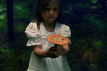 Caucasian girl holding mushroom in forest