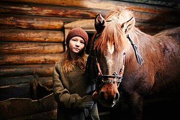 Caucasian teenage girl standing with horse in barn