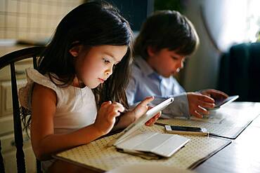 Caucasian brother and sister using digital tablets