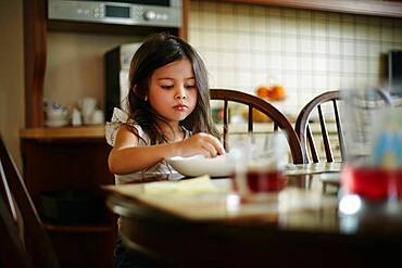 Caucasian girl eating at kitchen table