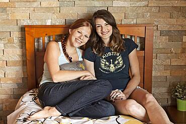 Students hugging on bed in dorm room