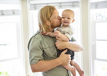 Caucasian father kissing son indoors