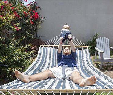 Caucasian father and son playing on hammock