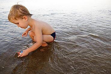 Caucasian boy playing in water on beach