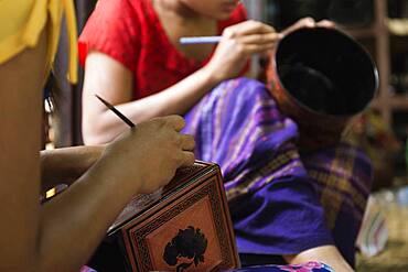 Asian artisans carving traditional design in workshop