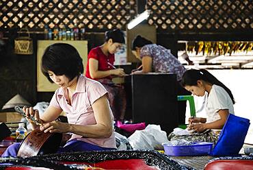 Asian artisans carving traditional designs in workshop