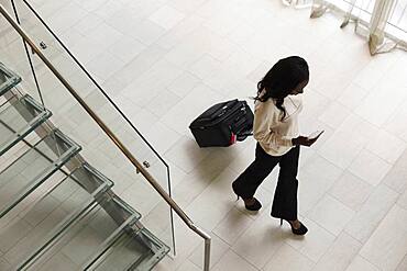 High angle view of businesswoman rolling luggage in hotel lobby