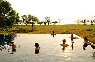 Tourists swimming in infinity pool in remote landscape