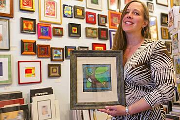 Caucasian artist holding artwork in gallery