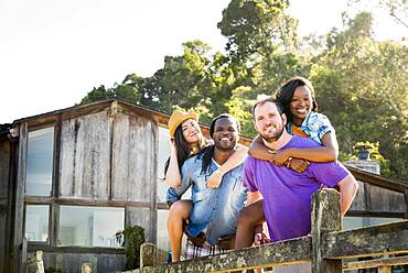 Men carrying girlfriends piggyback outdoors