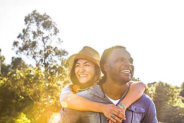 Man carrying girlfriend piggyback outdoors