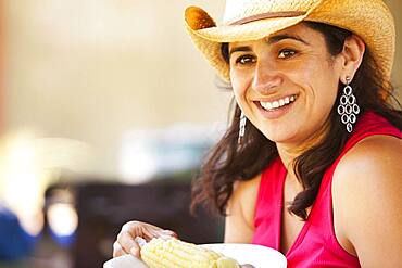 Smiling Hispanic woman eating corn