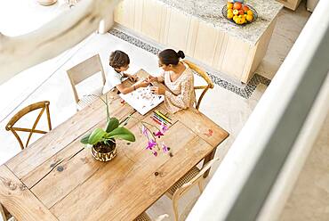 Hispanic mother and son playing game at table