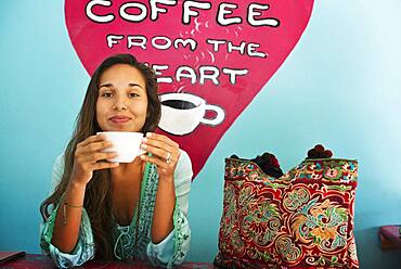 Hispanic woman drinking coffee in cafe