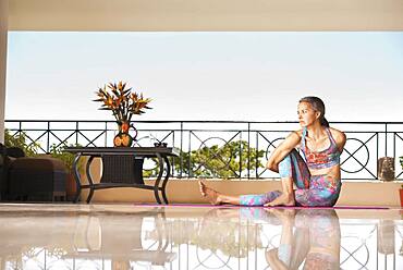 Hispanic woman practicing yoga on balcony