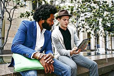 Businessmen using digital tablet outdoors