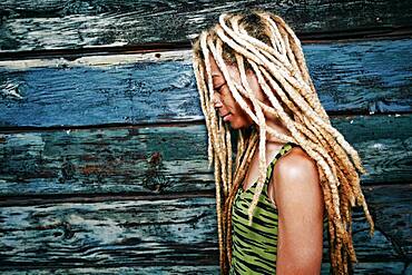 Black woman with dreadlocks at wooden wall