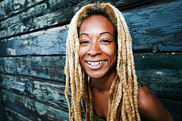 Black woman smiling at wooden wall