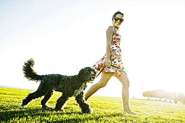 Caucasian woman walking dog in field