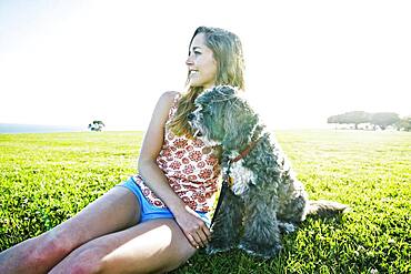 Caucasian woman sitting in field with dog