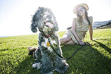 Caucasian woman sitting in field with dog