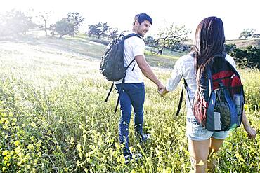 Couple carrying backpacks in field