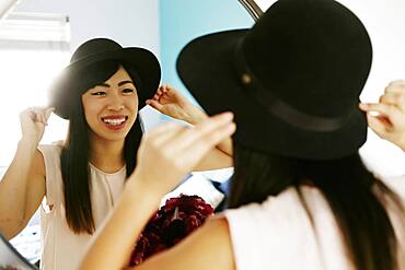 Japanese woman adjusting hat in mirror