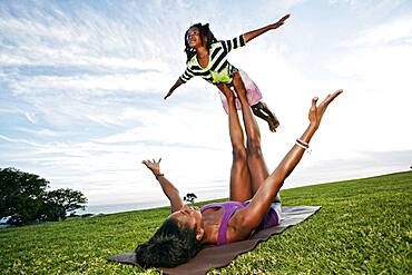 Mother balancing daughter on legs in park