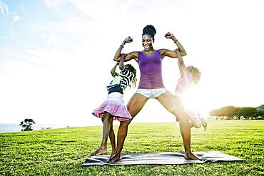 Woman lifting children with biceps in park