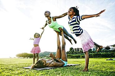 Family practicing acro yoga in park