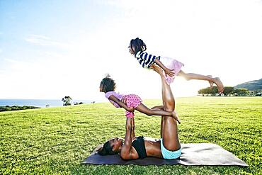 Mother holding children on yoga mat in park