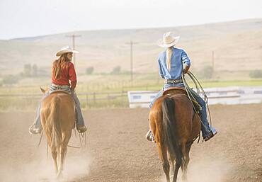 Caucasian cowgirls riding horses on ranch