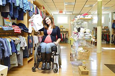 Pregnant paraplegic woman in wheelchair shopping in baby store