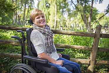 Paraplegic woman in wheelchair smiling in garden