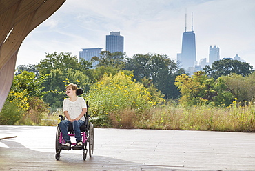 Paraplegic woman sitting in wheelchair under city skyline