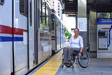 Disabled woman in wheelchair waiting in train station