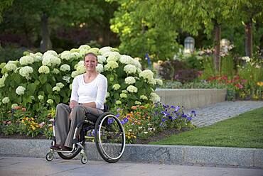 Disabled woman sitting in wheelchair on city street