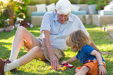 Caucasian grandfather and grandson playing on lawn