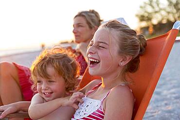 Caucasian children relaxing in lawn chair on beach