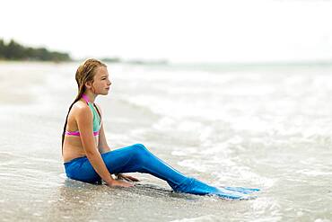 Caucasian girl wearing mermaid fin on beach