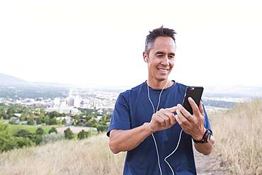 Mixed race man using cell phone on hilltop