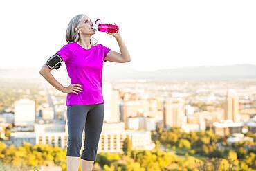 Caucasian woman drinking water bottle on urban hilltop