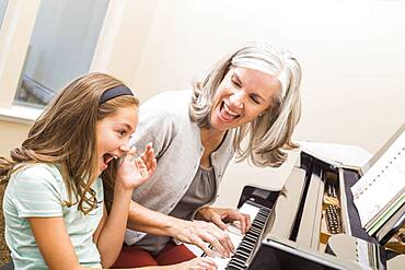 Caucasian grandmother and granddaughter playing piano