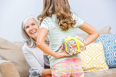 Caucasian girl hiding gift for grandmother behind back