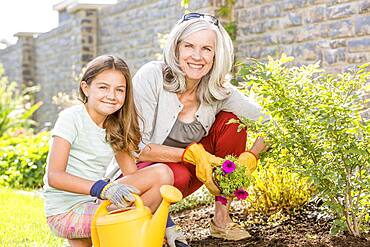 Caucasian grandmother and granddaughter gardening in backyard