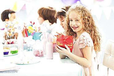 Girl holding wrapped gift at birthday party