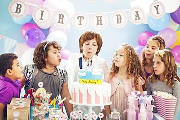 Boy blowing out candles on birthday cake at party