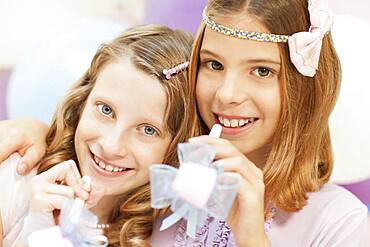 Smiling girls holding noisemakers at party