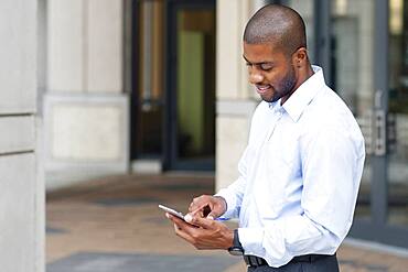 Black businessman using cell phone outside office